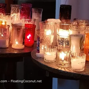 kaarsen in allerlei soorten, maten en kleuren op 2 tafeltjes in een kerk